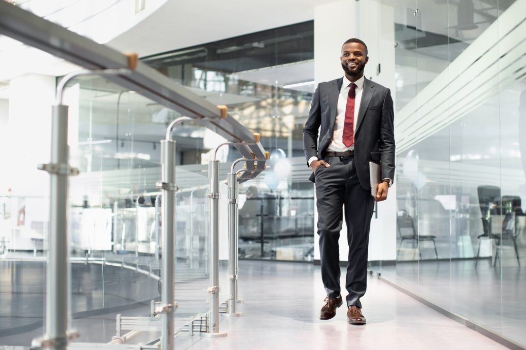 Positive black manager walking by office building